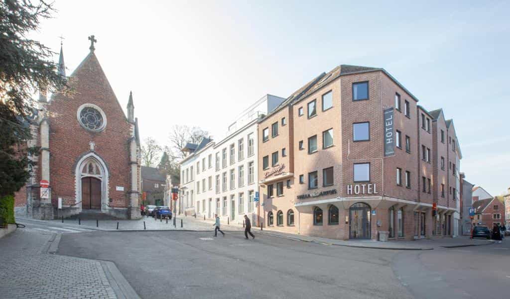 Brick church next to a modern hotel on a street corner in a European town.