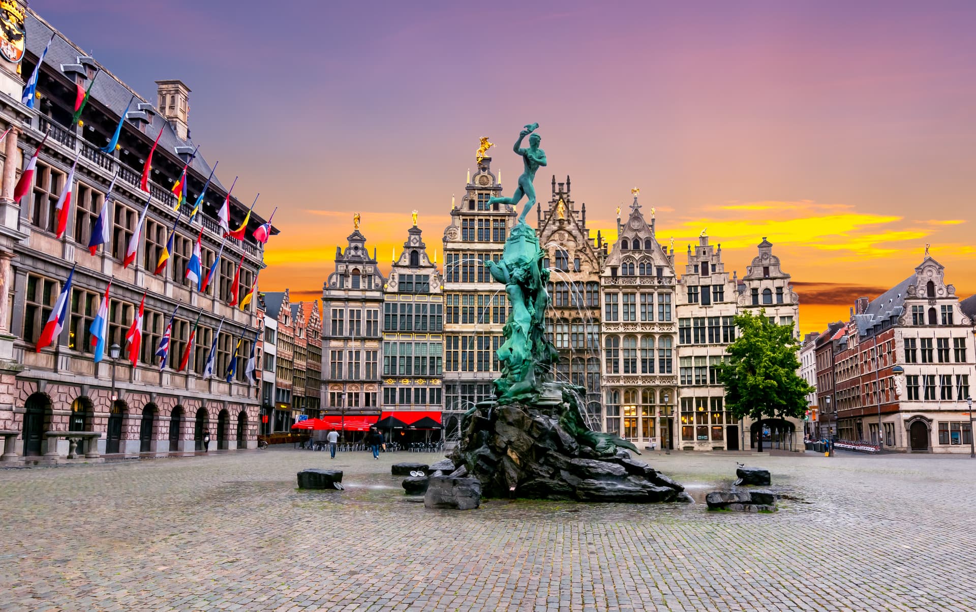 Brabo Fountain in Grote Markt square with guild houses at sunset in Antwerp.