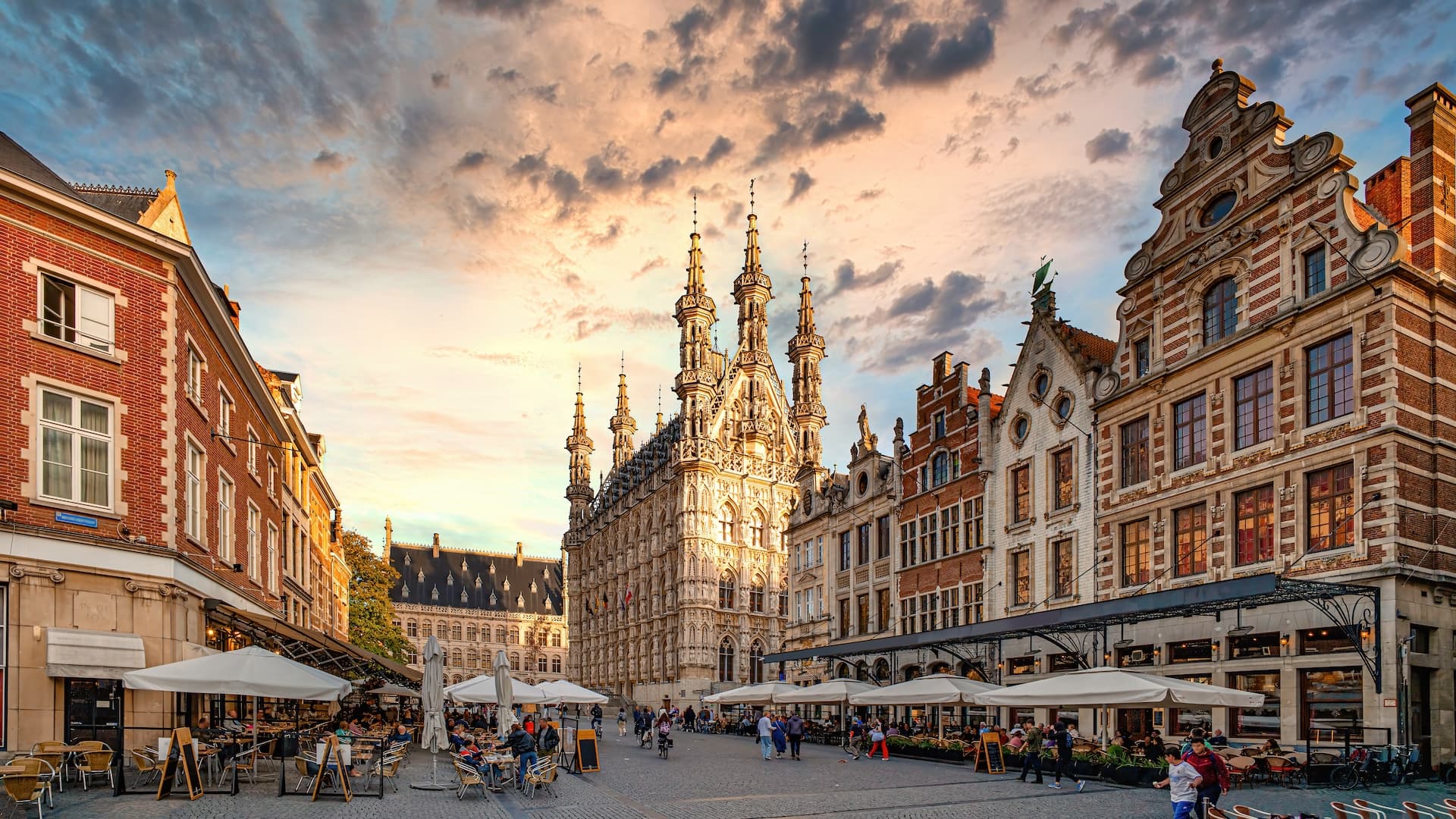 Gothic town hall and historic buildings with outdoor cafe seating in a European square