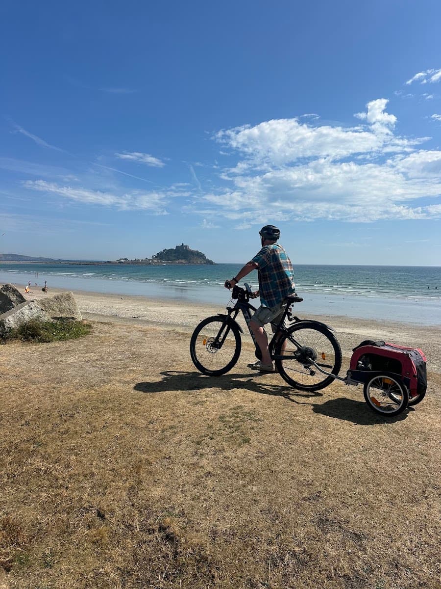 Cyclist with bike trailer overlooking coastal beach and distant island castle