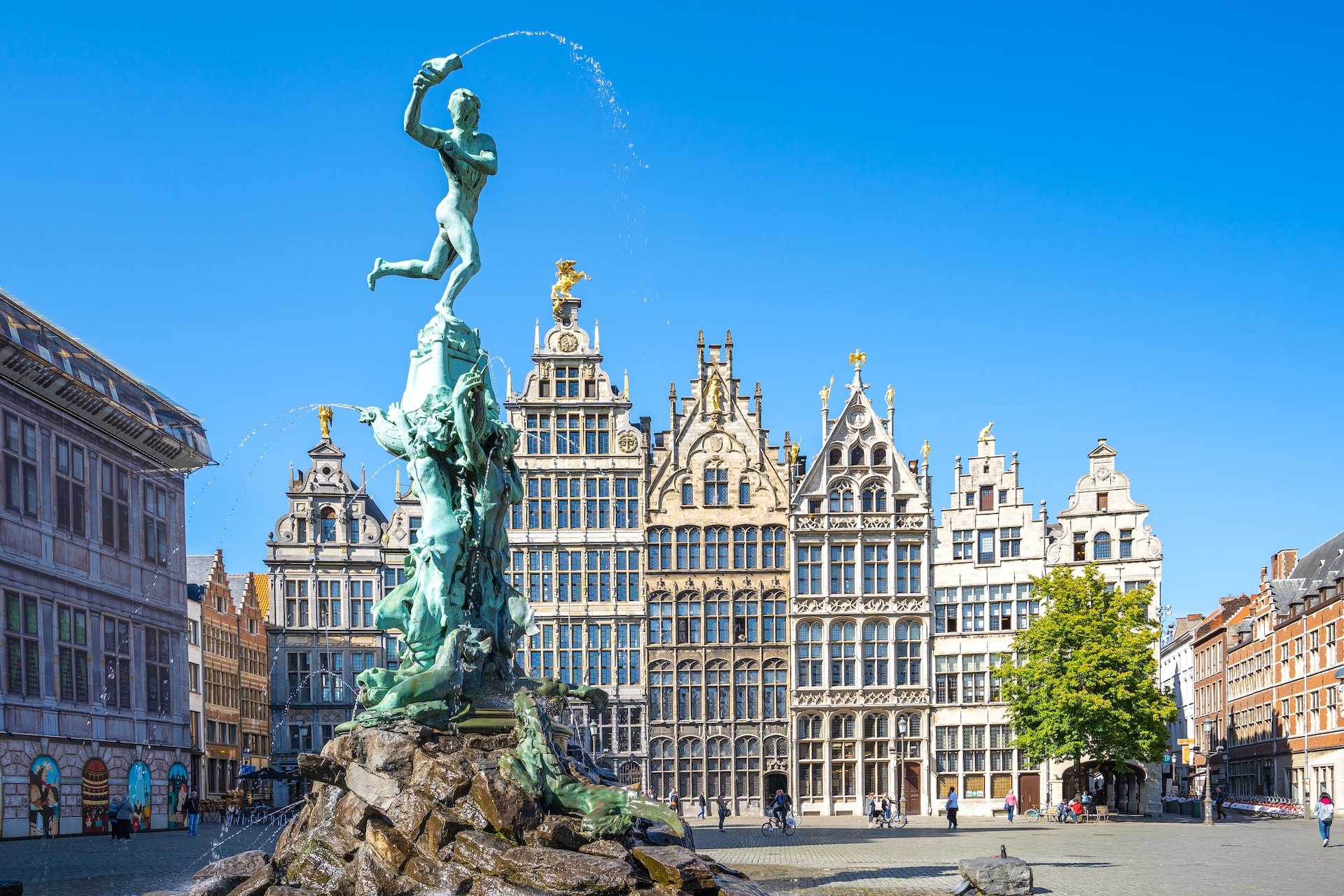 Brabo Fountain spraying water in Grote Markt square with guildhalls in Antwerp.