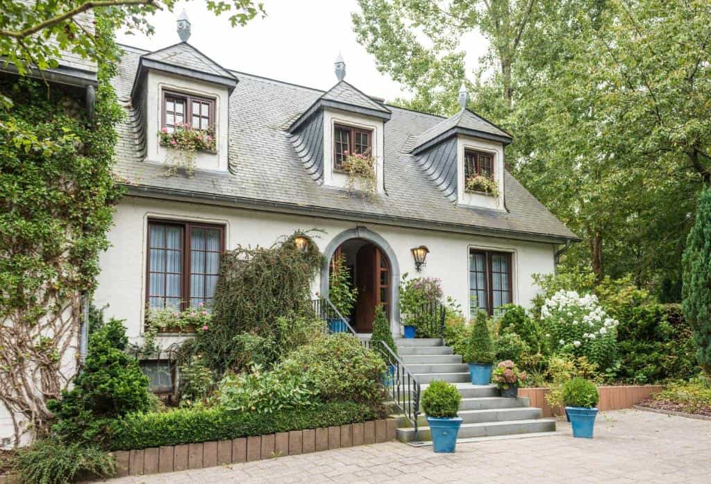 White house with slate roof, dormer windows, and lush green landscaping, Steineweiher.