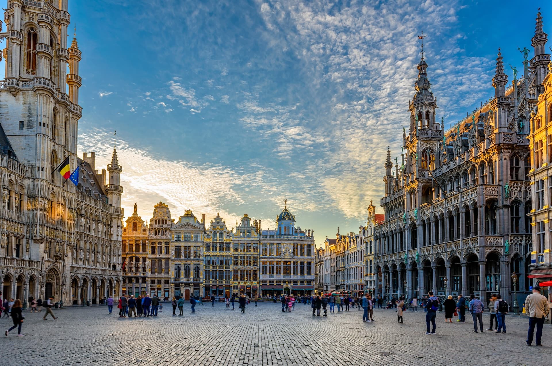 Grand Place Brussels with ornate guildhalls under a dramatic sky at sunset.