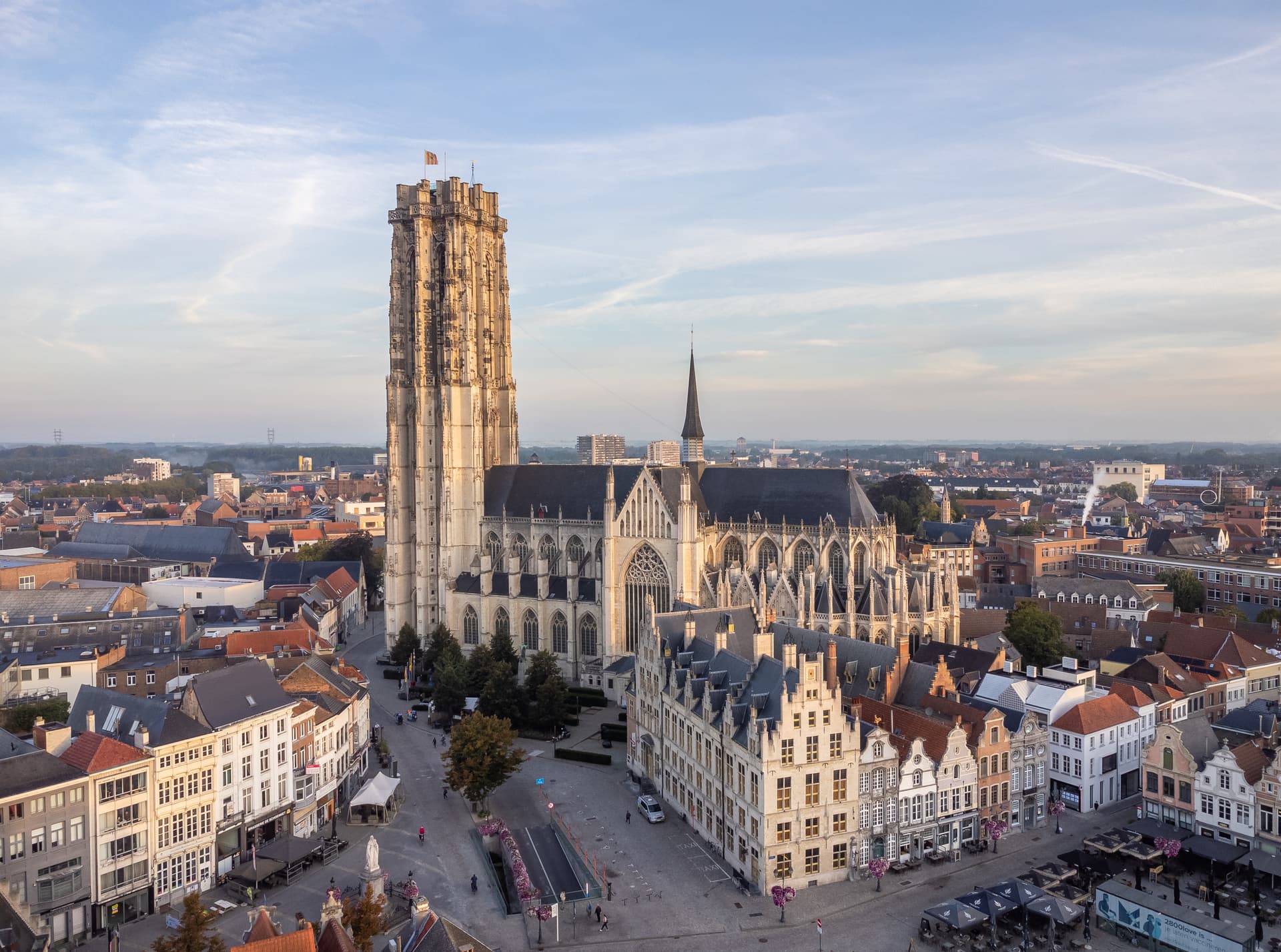 St. Rumbold's Cathedral tower overlooking the historic city center under a pale blue sky.