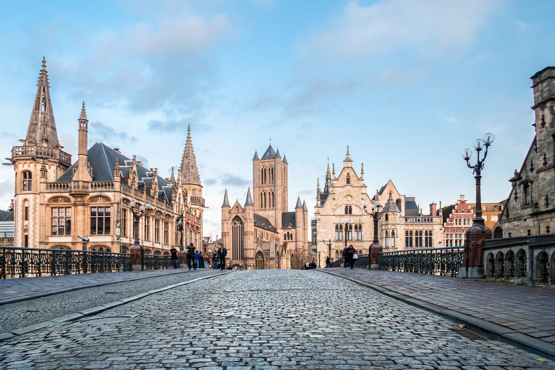 Cobblestone street leading to historic guild houses and St. Nicholas' Church in Ghent.
