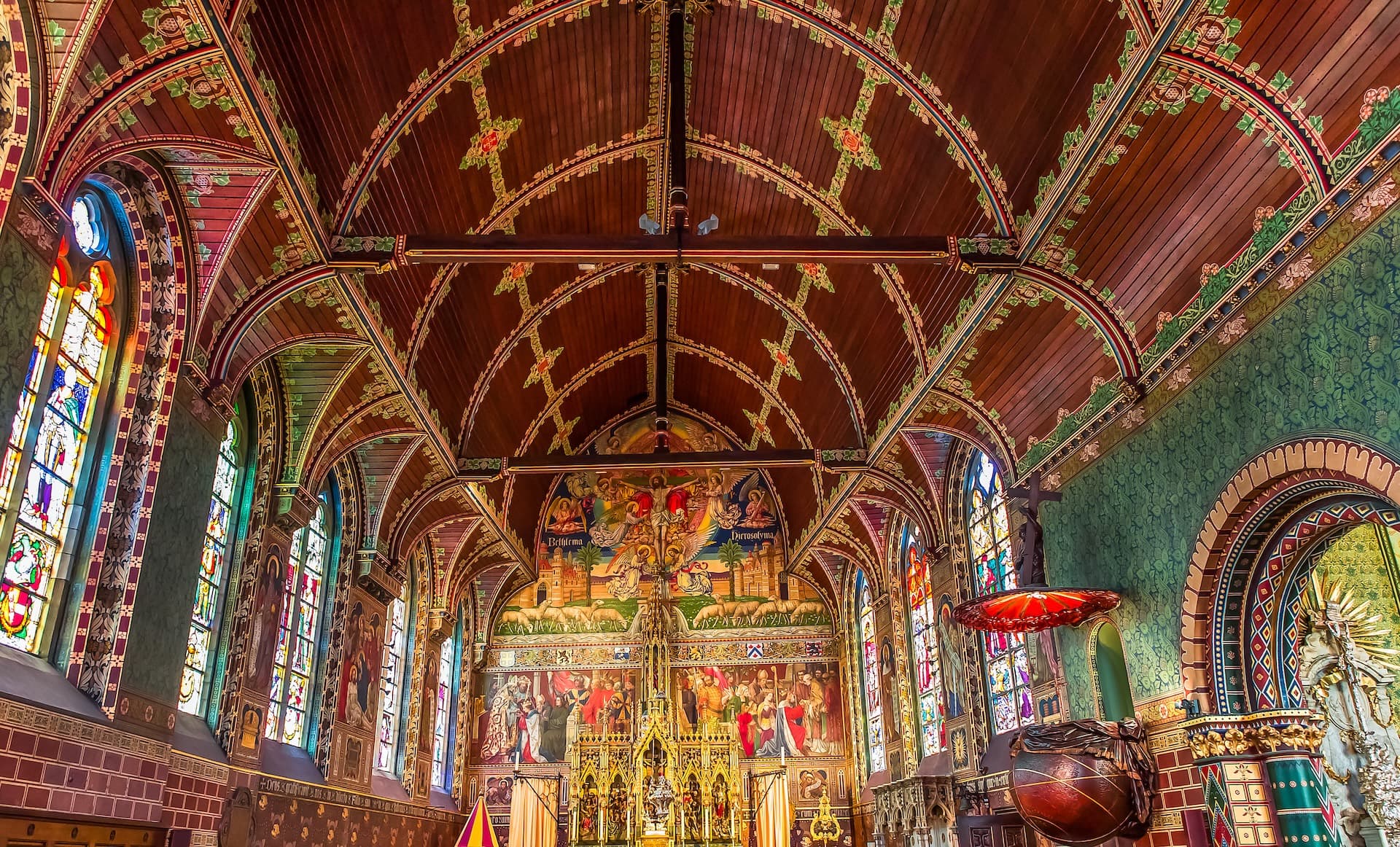 Basilica of the Holy Blood interior with ornate wooden ceiling, stained glass windows, and colorful altar murals.